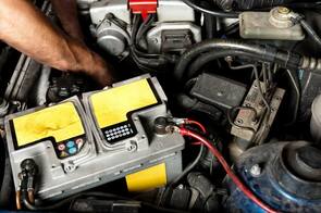 Auto electrician replacing a battery inside and engine bay